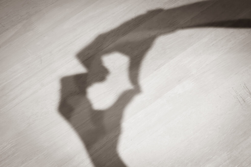 Schatten von zwei Händen auf heller Flaeche, die Finger formen ein Herz