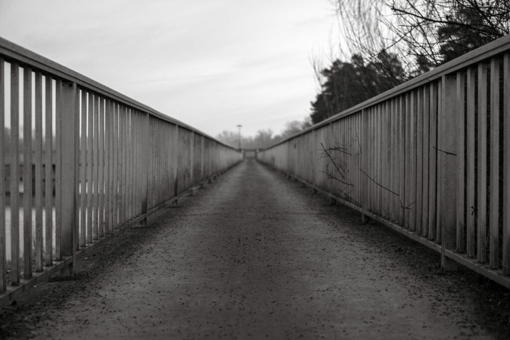 Schwarz-weiß Foto einer langen Brücke mit Geländern links und rechts.
