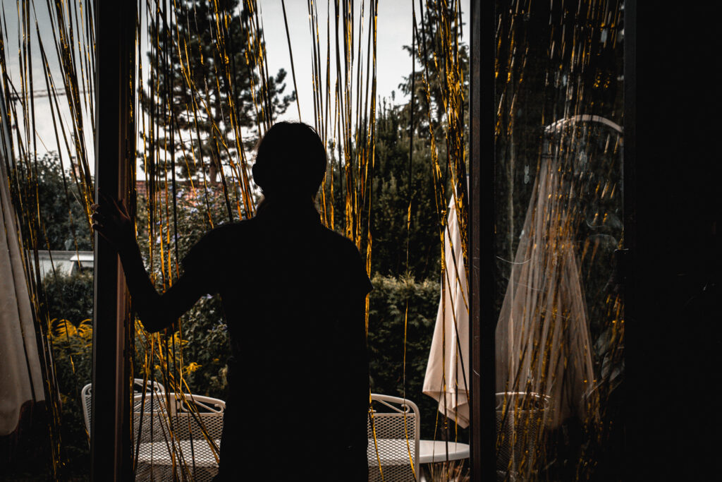 Silhouette einer Person in einer geöffneten Terrassentür mit Blick auf den Garten.